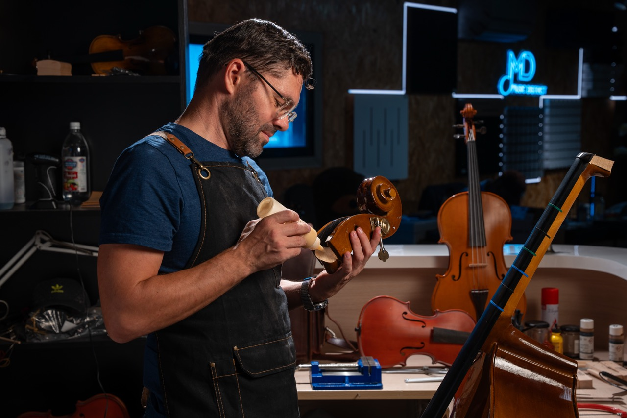 Music District specialist working on a cello in the workshop