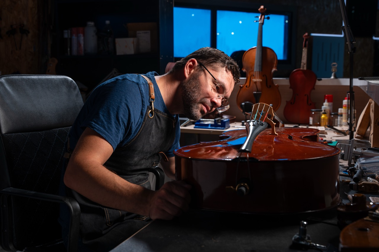 Andriy inspecting a cello in the Music District luthier workshop