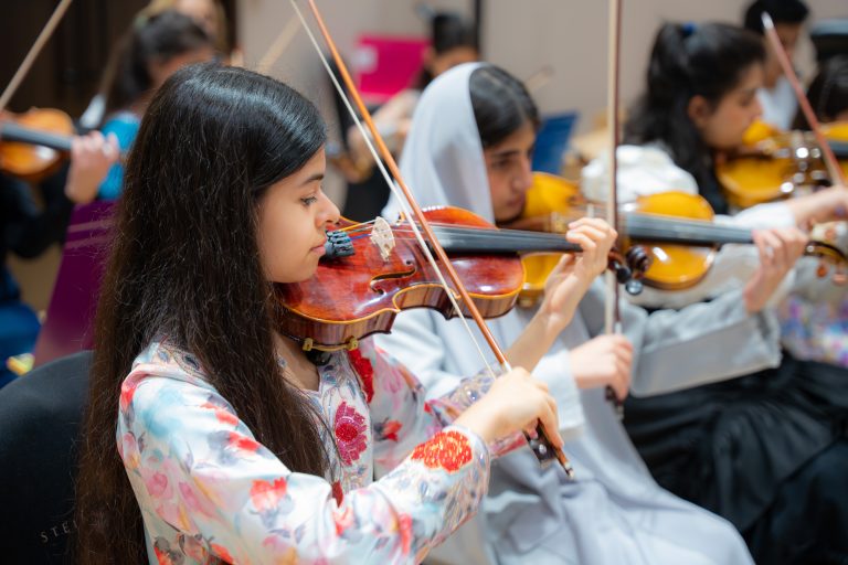 Young musicians rehearsing on violin in the Empowering Emirati Musicians Program